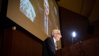 Lord Martin Rees at the podium, with photo of Carl Sagan in background