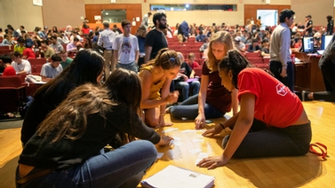 group of students examines index cards laid out on the floor
