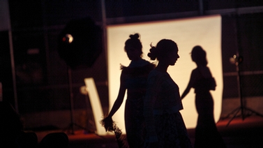 Three women in silhouette backstage.