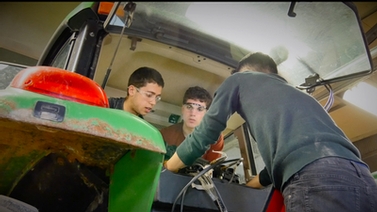 students work on the tractor in the shop