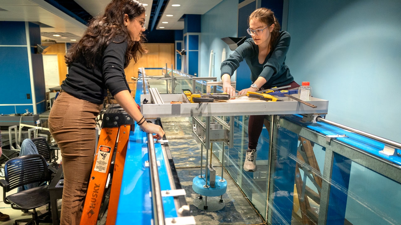 Kavya Mittha and Aisha Brundan prepare to submerge and test their bobbing buoy wave energy converter at the DeFrees Hydraulics Lab in Hollister Hall.