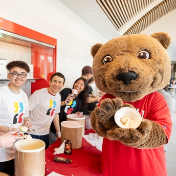 与微笑的学生一起触摸拿着冰淇淋的熊。 