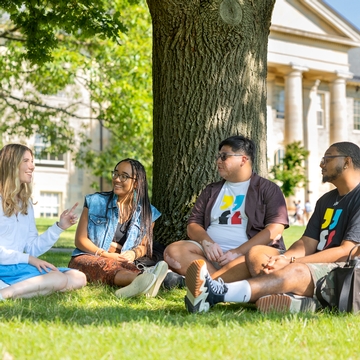 Four students sitting on the Arts Quad