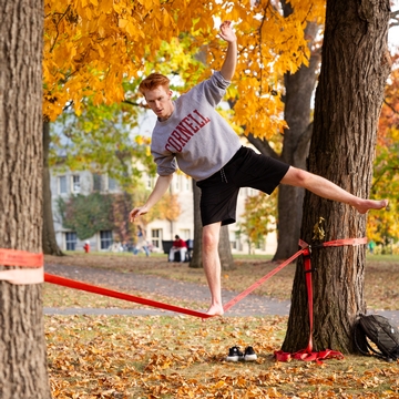 A Cornell student slacklining on the Arts Quad.