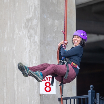 A person smiling repelling from schoellkopf stadium