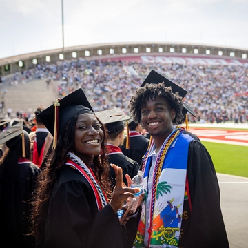 Two students smiling during commencement. 