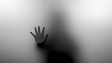 blurred silhouette of a person with hand against glass