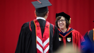 President Martha E. Pollack congratulates a graduate student onstage in Barton Hall.