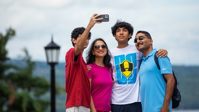 A group of four people take a family photo of themselves.