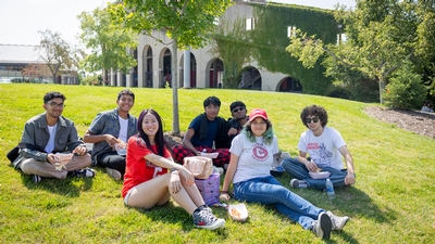 Students sitting in the grass smiling. 